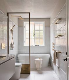 a white bathroom with a tub, toilet and window in the corner on the wall