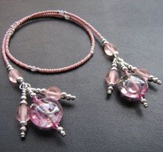 two bracelets with pink beads and charms on a black surface, next to each other