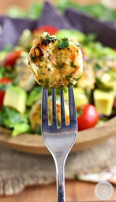 a fork with food on it is in front of a salad