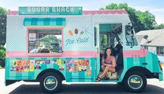 a woman is sitting in the front of a ice cream truck that sells frozen treats