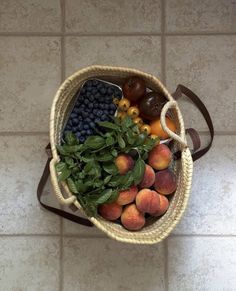 a basket filled with fruit sitting on top of a tiled floor