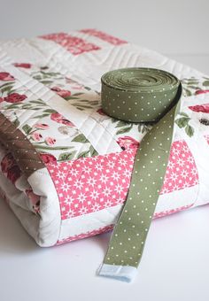 a roll of fabric sitting on top of a piece of cloth with a green ribbon