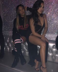 two beautiful women sitting on top of a couch