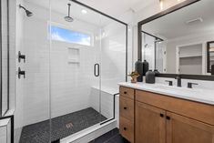 a bathroom with a walk in shower next to a white sink and wooden cabinetry