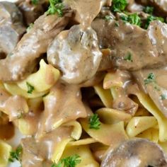 pasta with meat and mushroom sauce on it is sitting on a white plate, ready to be eaten