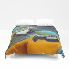 a bed covered in a yellow and blue comforter with two parrots on it