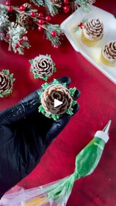 someone is holding up some cupcakes on a table with other christmas decorations around them