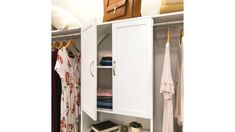 an open closet with clothes and books on the shelf, next to a plant in a vase