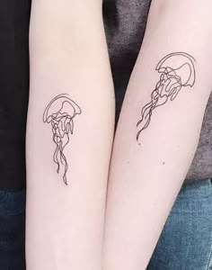 two people with matching tattoos on their arms holding each other's hands and one has a jellyfish tattoo on its arm