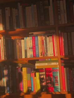 a bookshelf filled with lots of different colored books on top of wooden shelves