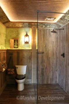 a bathroom with a toilet, shower and wood paneling on the walls is shown