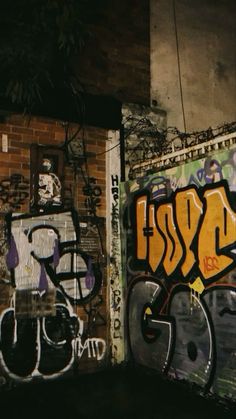 graffiti on the side of a brick wall in an alleyway at night with no one around