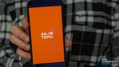 a person holding an orange cell phone with the temu app on it's screen