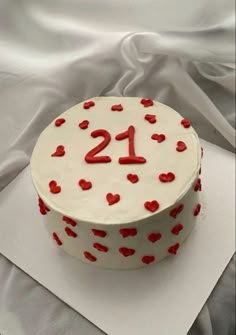 a white cake with red hearts on it and the number twenty one is decorated in red icing