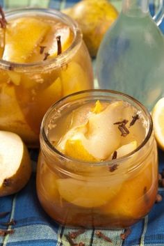 two jars filled with lemon and apple cider on a blue table cloth next to sliced apples