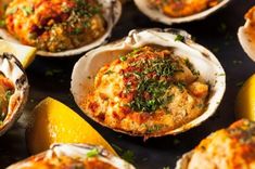 several open oysters on a plate with lemon wedges