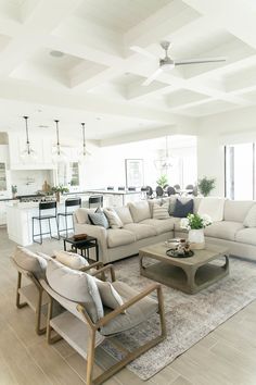 a living room filled with furniture and a kitchen in the backgroung area