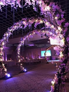 an archway decorated with purple flowers and lights