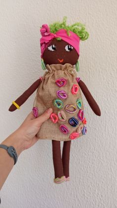 a hand is holding a small doll with donuts on it