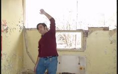 a man standing in the corner of a room with peeling paint on the walls and ceiling