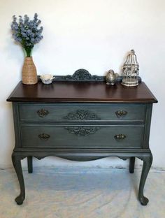 an old dresser with flowers and a birdcage on top