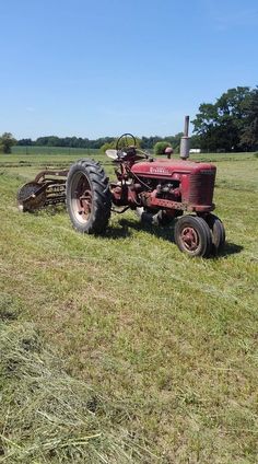 an old red farmall tractor sitting in the middle of a field