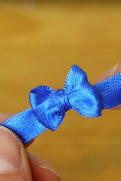 a person holding a small blue bow in their hand