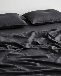 a bed with black sheets and pillows on it