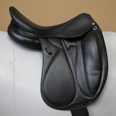 a close up of a black saddle on a white horse