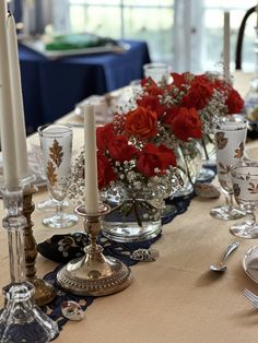 the table is set with silverware and red roses