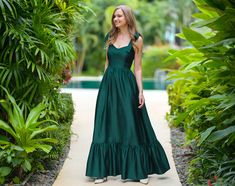 a woman in a long green dress standing on a path