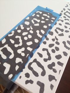 an animal print is being painted on top of a piece of paper with blue tape