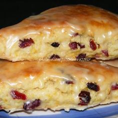 two scones sitting on top of a plate covered in icing and cranberries