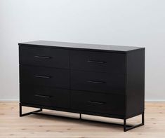 a black dresser sitting on top of a wooden floor