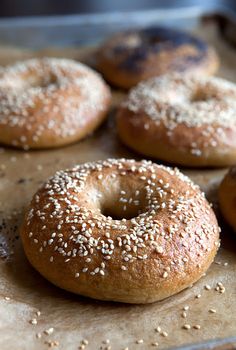 several bagels with sesame seeds on a baking sheet, ready to be baked in the oven