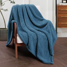 a blue blanket sitting on top of a wooden chair next to a potted plant