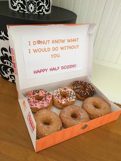 a box filled with donuts sitting on top of a wooden table next to a sign that says i donut know what i would do without you