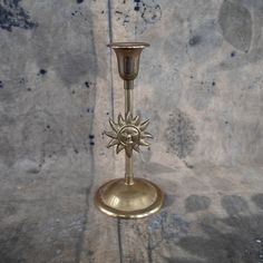 a brass candle holder with a sun on it