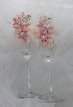 two wine glasses with pink flowers and pearls on the rims, sitting side by side