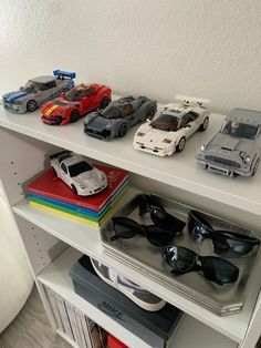 some toy cars are sitting on top of a book shelf in front of a white wall