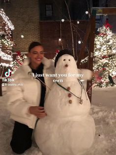 a woman standing next to a snowman in front of christmas trees with lights on it