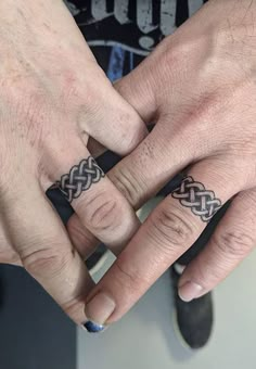 two people holding hands with tattoos on their fingers