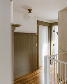 an empty room with hard wood floors and white railings on either side of the door