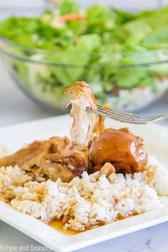 someone is eating some food with a fork on top of rice and salad in the background