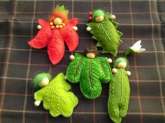 four green and red flowers sitting on top of a plaid cloth