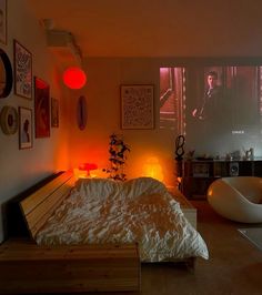 a bed room with a neatly made bed next to a projector screen and pictures on the wall