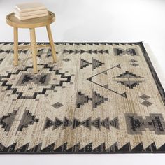 a table and chair on top of a rug with an area rug in the middle