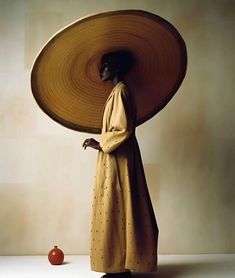 a woman with a large hat on her head and an apple in the foreground