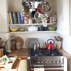 a stove top oven sitting inside of a kitchen next to a wooden counter topped with pots and pans