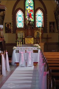 the interior of a church decorated with white and pink sashes, pews and stained glass windows